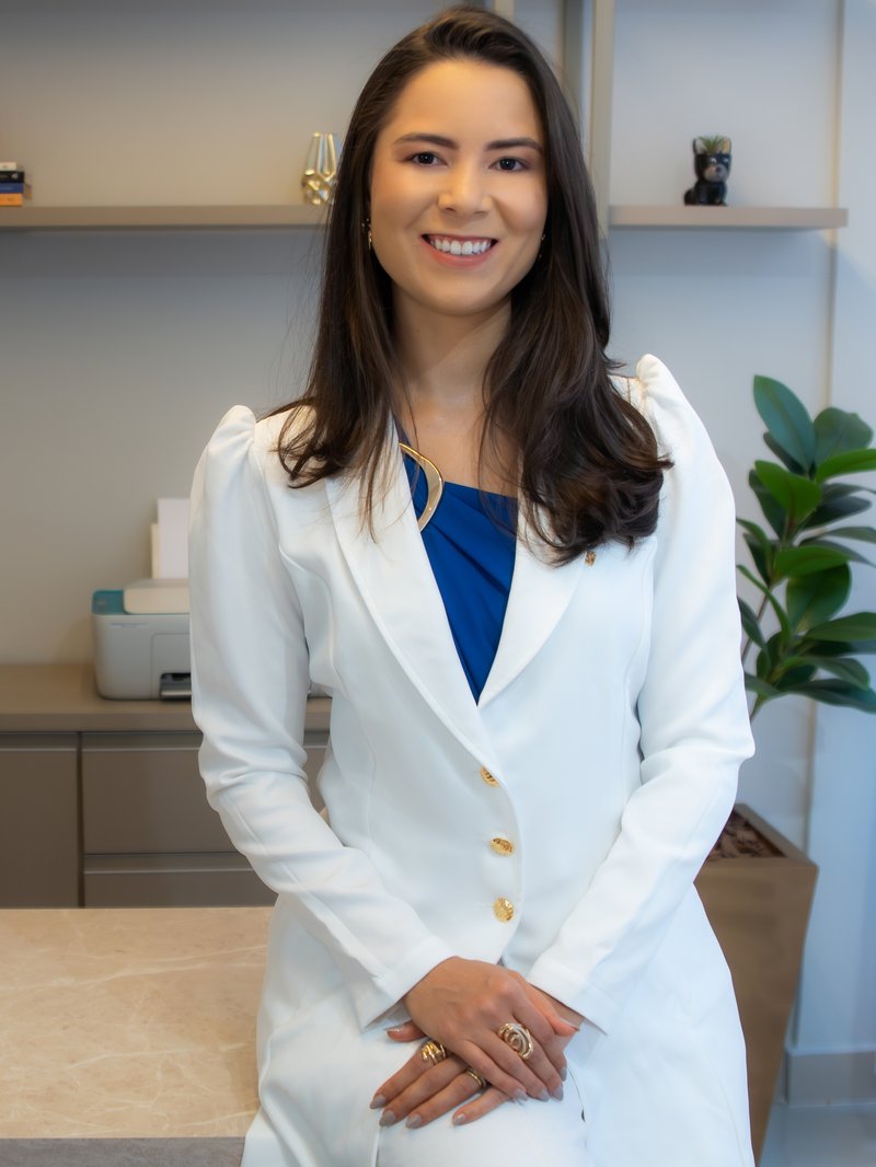 Dra. Rebeca Miranda em seu consultório, em pé próxima à bancada